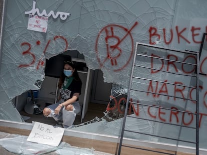 Uma manifestante dentro de um caixa de bitcoins destruído durante os protestos de quarta-feira.