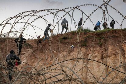 Palestinos atraviesan una valla de alambre hacia Israel para llegar a sus lugares de trabajo cerca del puesto de control israelí de Mitar, cerca de Hebrón, en Cisjordania.