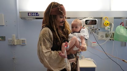 El actor estadounidense sujeta a un bebé durante su visita al hospital Donostia, este jueves.