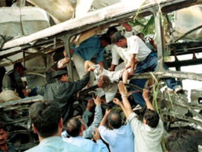 Un grupo de voluntarios traslada uno de los cadáveres de las víctimas del atentado contra un autobús en Karachi.