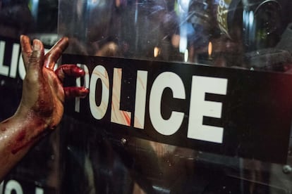 Una mujer se limpia la mano de sangre en un escudo de la policía antidisturbios em Charlotte, Carolina del Norte (Estados Unidos). 