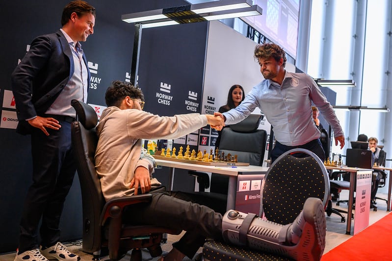 Carlsen saluda a Firouzja, lesionado en el tobillo derecho, al inicio de la primera ronda del torneo Norway Chess en Oslo, este lunes