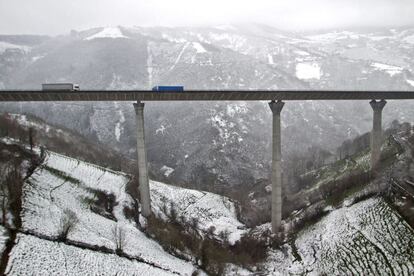 Dos camiones circulan por el puente de San Pedro de la A-6, cerca de Doncos (Lugo), en medio de un paisaje nevado.