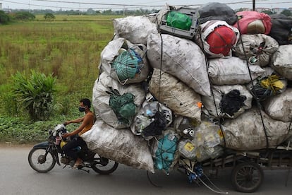 Una persona transporta residuos de plástico para su reciclaje en los suburbios de Hanoi (Vietnam).
