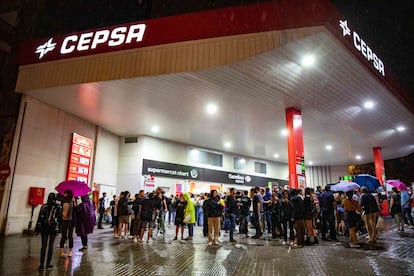 Jóvenes bajo el techo de una gasolinera del Paral.lel, mientras llovía, en la primera noche de las fiestas de la Mercè de Barcelona.