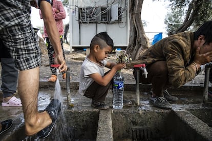 Em uma das principais avenidas do campo, uma fonte serve como ponto de encontro para refugiados. No mesmo local em que escovam os dentes, els lavam os pratos, os pés ou, como a criança na imagem, enchem garrafas de água como um vaso para algumas flores.