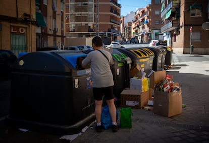 Un hombre tira la basura junto a unas cajas acumuladas junto a los contenedores en Usera, el jueves.