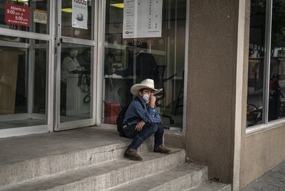 Un niño espera a su madre afuera de un banco en el centro de Milpa Alta.