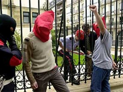Un grupo de miembros de las Juventudes Socialistas EGAZ, encapuchados, se han encadenado la verja del Parlamento Vasco para exigir más protección para los cargos electos del PP y del PSE.