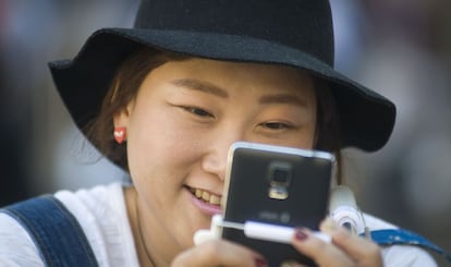 Uma turista asiática olha seu telefone celular.