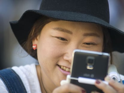 Uma turista asiática olha seu telefone celular.