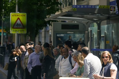Varios viandantes aguardan la llegada del autobús durante la interrupción en el suministro eléctrico, este lunes en Madrid.