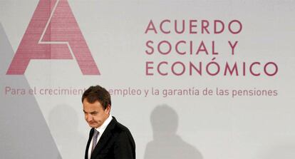 Zapatero pasa ante de uno de los carteles que anuncia el acuerdo social