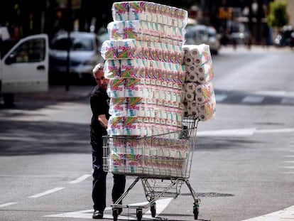 Um repositor empurra um carrinho com papel higiênico até uma loja em Málaga.