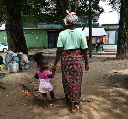 Evelyn geht im Mai 2025 mit einem Mädchen, das sie adoptiert hat, durch eine Gasse in Monrovia, der Hauptstadt Liberias.