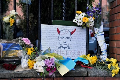 Una pancarta con la imagen de Putin y flores colocadas durannte una vigilia frente a la Embajada de Ucrania,  en Dublín, Irlanda.