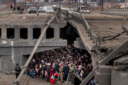 Ukrainians crowd under a destroyed bridge as they try to flee across the Irpin River on the outskirts of Kyiv, Ukraine, Saturday, March 5, 2022.