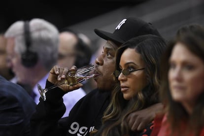 Jay-Z bebe champán sentado al lado de su esposa, la cantante Beyoncé, durante un partido de la NBA el pasado mayo.