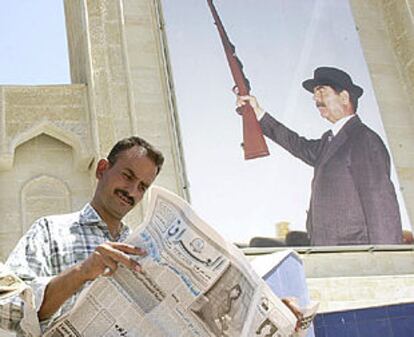 Un iraquí lee el diario <b><i>Iraq,</b></i> ayer, ante un retrato gigante de Sadam Husein.