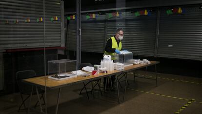 Un operario coloca el material electoral para los comicios del domingo en el Mercado del Ninot (Barcelona).