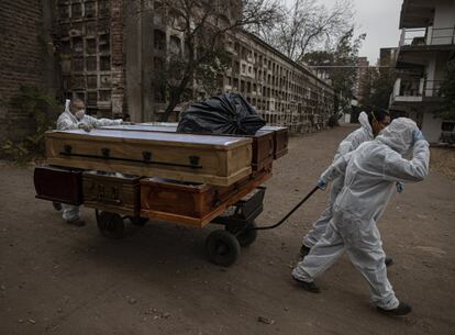 Trabajadores funerarios retiran los ataúdes vacíos tras la incineración de los cuerpos en el cementerio de La Recoleta, en Santiago de Chile, el martes 20 de abril de 2021, durante la pandemia de coronavirus.