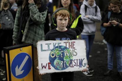 El movimiento XR anunció que el jueves 25 de abril pondrá fin a sus bloqueos en Londres, tras once días de acciones para reclamar un 'estado de emergencia ecológico'. En la foto, un joven manifestante sostiene una pancarta mientras bloquean una carretera en el centro de Londres, miércoles 24 de abril de 2019.