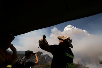 Los bomberos han tenido dificultades para extinguir las llamas por tratarse de “incendios con comportamiento muy extremo por su alta velocidad de propagación", afirmó el gerente de protección de la Corporación Nacional Forestal, Pablo Lobos. En la imagen, voluntarios graban el incendio de Curacavi con sus teléfonos celulares. 