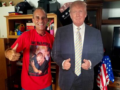Gene Huber posa junto a un recorte de Trump de tamaño real en el salón de su casa.