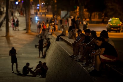 Varias personas disfrutan del ambiente en la playa de la Barceloneta, durante la noche.