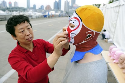 Zhang Shifa, creadora del 'facekini', ayuda a uno de sus clientes a colocarse la prenda en su tienda en la ciudad costera de Qingdao.