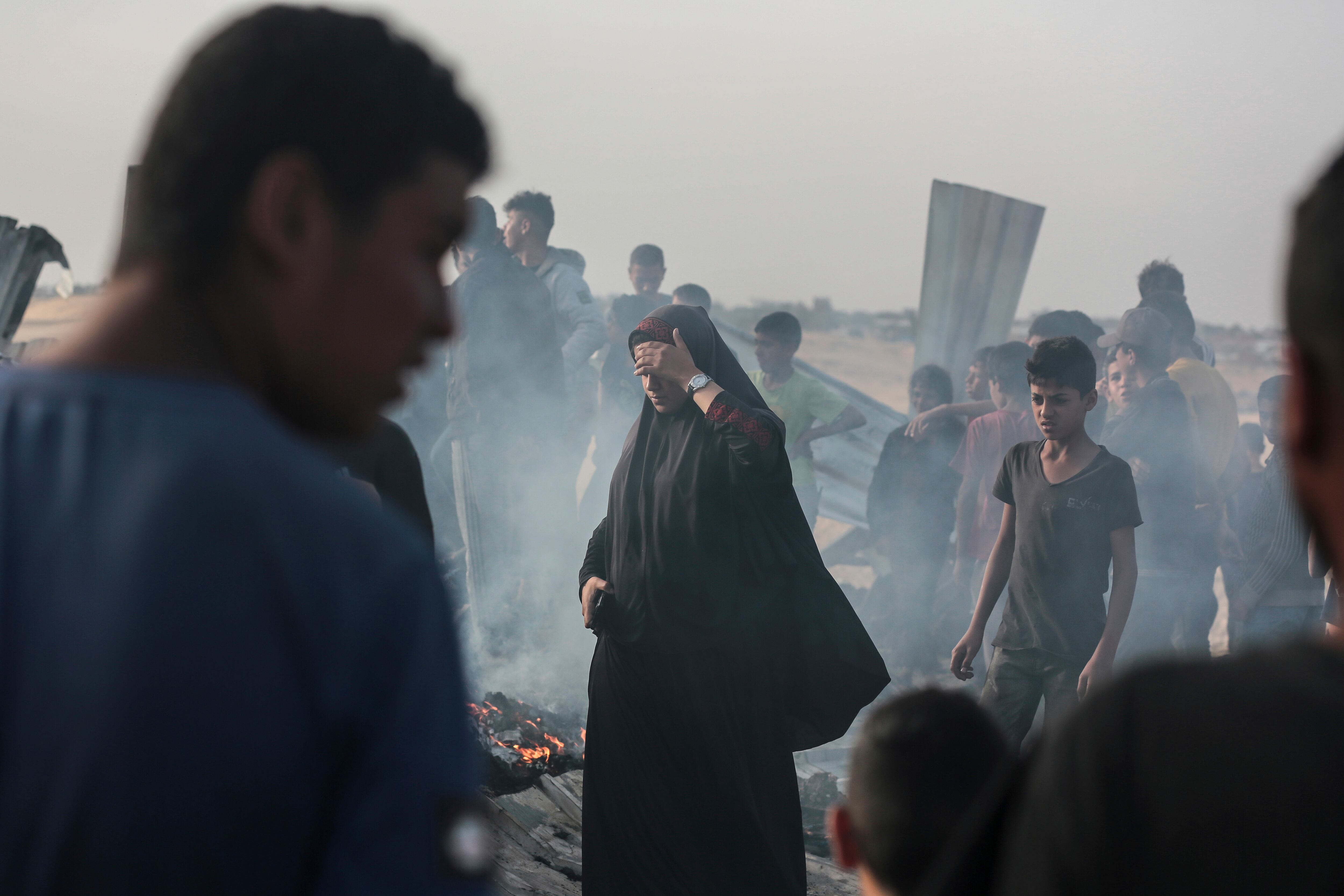 Un grupo de gazatíes inspecciona los restos aún humeantes de la zona bombardeada por Israel. 