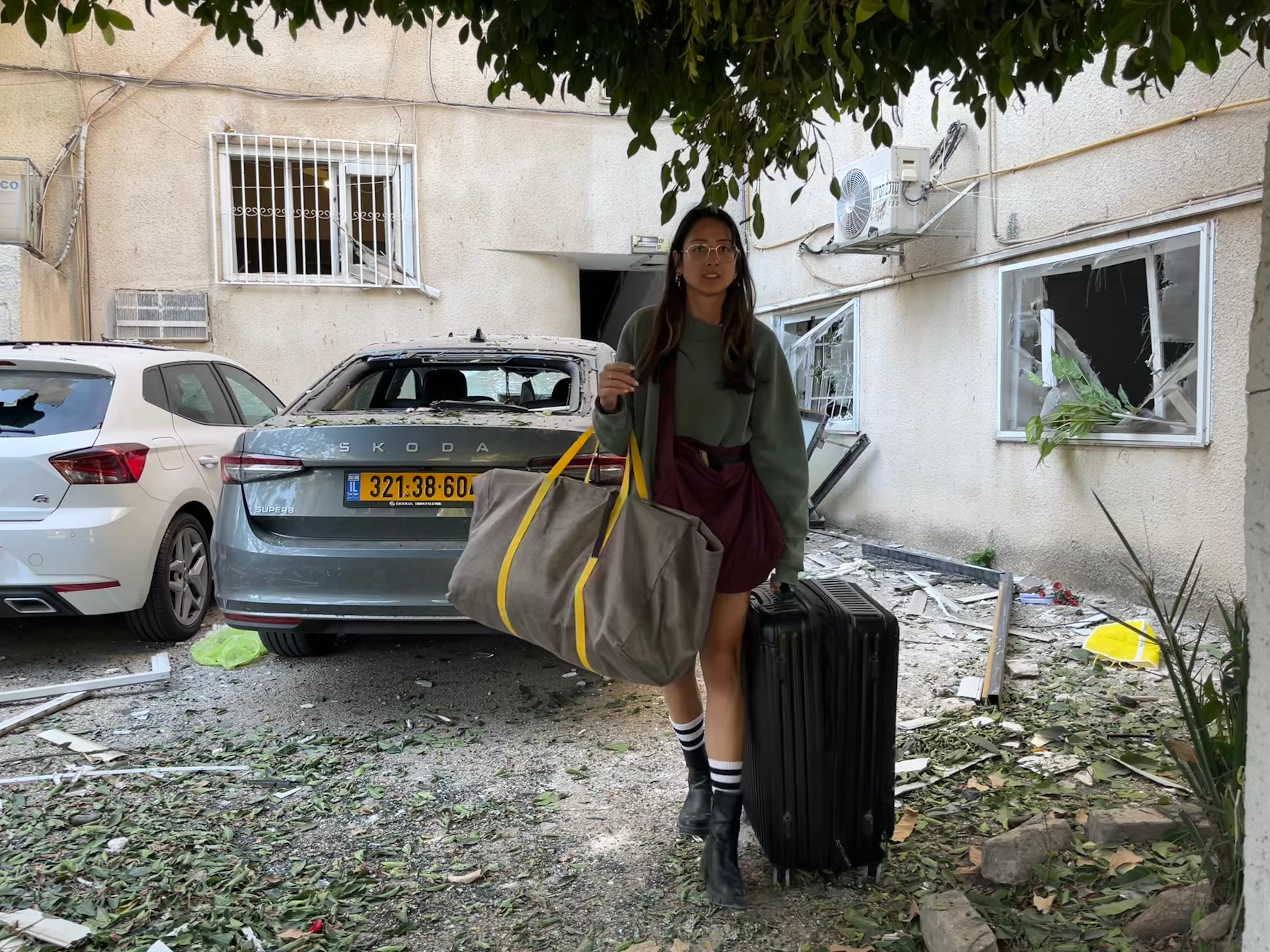 Una israelí abandona con una maleta su casa en Tel Aviv, que tiene que evacuar porque resultó dañada en la víspera por un misil israelí, este domingo. / ANTONIO PITA