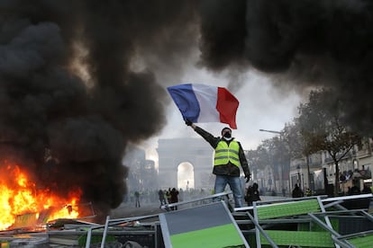 Un manifestante ondea la bandera de Francia frente a una barricada en llamas en los Campos Elíseos (Francia) durante las protestas de los 'chalecos amarillos' contra el aumento de los impuestos de la gasolina, el 24 de noviembre pasado. Miles de personas se concentraron para expresar su inconformidad frente a las medidas económicas del presidente Emmanuel Macron.