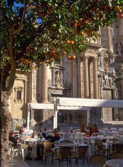 Terraza en la plaza del Cardenal Belluga, en Murcia, y la fachada barroca de la catedral.