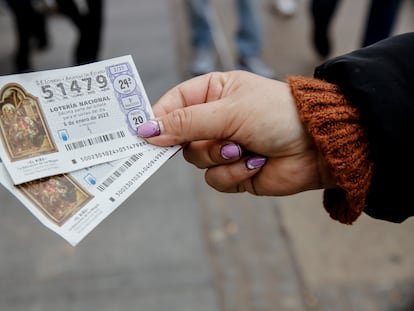 Una mujer sostiene dos décimos para el Sorteo Extraordinario del Niño, en Madrid (España).