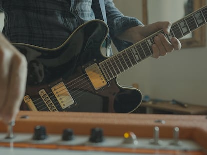 Un guitarrista rock toca la guitarra eléctrica en casa.