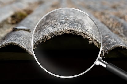 Old and very dangerous asbestos roof. Asbestos dust in the environment. Health problems. View through magnifying glass - La ciencia que nos une - amianto - mesotelioma