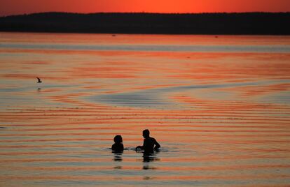 Una pareja disfruta la puesta de sol en un lago en las afueras de Minsk (Bielorrusia).