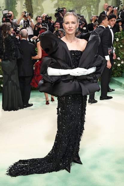 Naomi Watts reinventa el Hollywood clásico con un vestido negro palabra de honor combinado ocn guantes blancos, chal acolchado y un tocado de red. Todo es de Balenciaga.