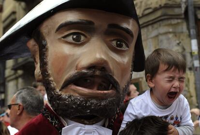 Un niño se asusta con uno de los cabezudos durante el desfile de comparsas.