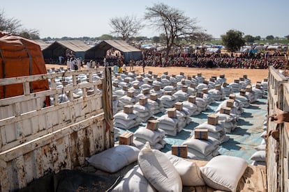 Se han utilizado postes de acero y finas cuerdas de colores para crear una barrera que separa a decenas de miles de sudaneses de las bolsas de sorgo, guisantes y botellas de aceite de palma que distribuye el Programa Mundial de Alimentos (PMA). Como en el resto del campamento, únicamente hay unos pocos árboles que den sombra. En las pocas tiendas de campaña instaladas apenas caben unas decenas de personas, por lo que la mayoría espera bajo un sol abrasador, que se vuelve cada vez más ardiente a medida que avanza la mañana.