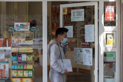 Un joven sale de una farmacia que anuncia en su fachada que tiene mascarillas en Madrid.