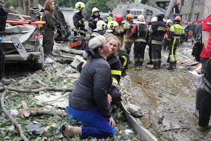 Una mujer es consolada por una militar mientras llora en el lugar del ataque con misiles rusos en Kiev.