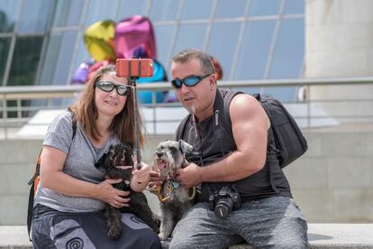 Dos personas, con sus mascotas, se toman un selfi frente al Guggenheim de Bilbao.