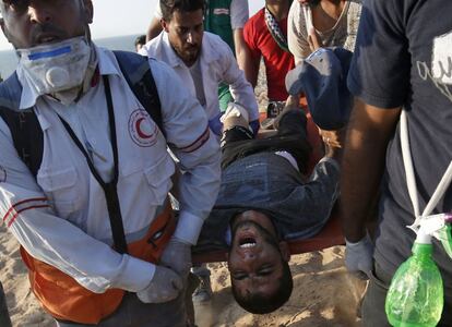 Manifestantes y paramédicos palestinos llevan a un herido en una camilla durante una protesta pidiendo el fin del bloqueo israelí en Gaza, en una playa en Beit Lahia, cerca de la frontera marítima con Israel.