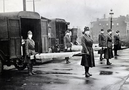 Empleados de la Cruz Roja en St. Louis (Misuri), durante la pandemia de gripe española de 1918. La imagen muestra a enfermeras con mascarillas sosteniendo camillas listas para entrar en las ambulancias.