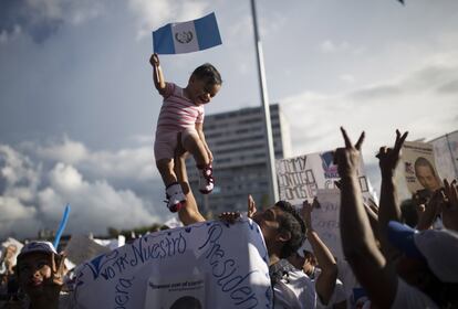 Un partidario de Jimmy Morales alza a un niño que lleva un banderín de Guatemala en la mano.