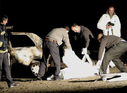 Miembros de los servicios funerarios trasladan el cuerpo carbonizado de la fallecida.