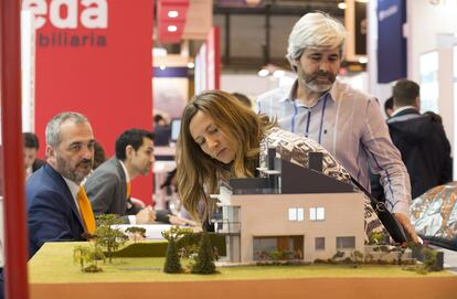 Visitantes del SIMA de Madrid miran una maqueta de una promoción de viviendas.