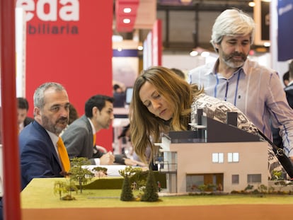 Visitantes del SIMA de Madrid miran una maqueta de una promoción de viviendas.